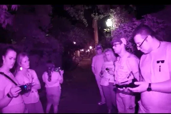 A ghost tour group exploring Charleston’s dark historic streets and alleys at night
