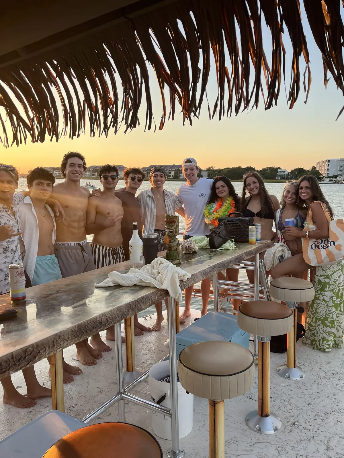Guests lined along the bar as the sun sets over the water
