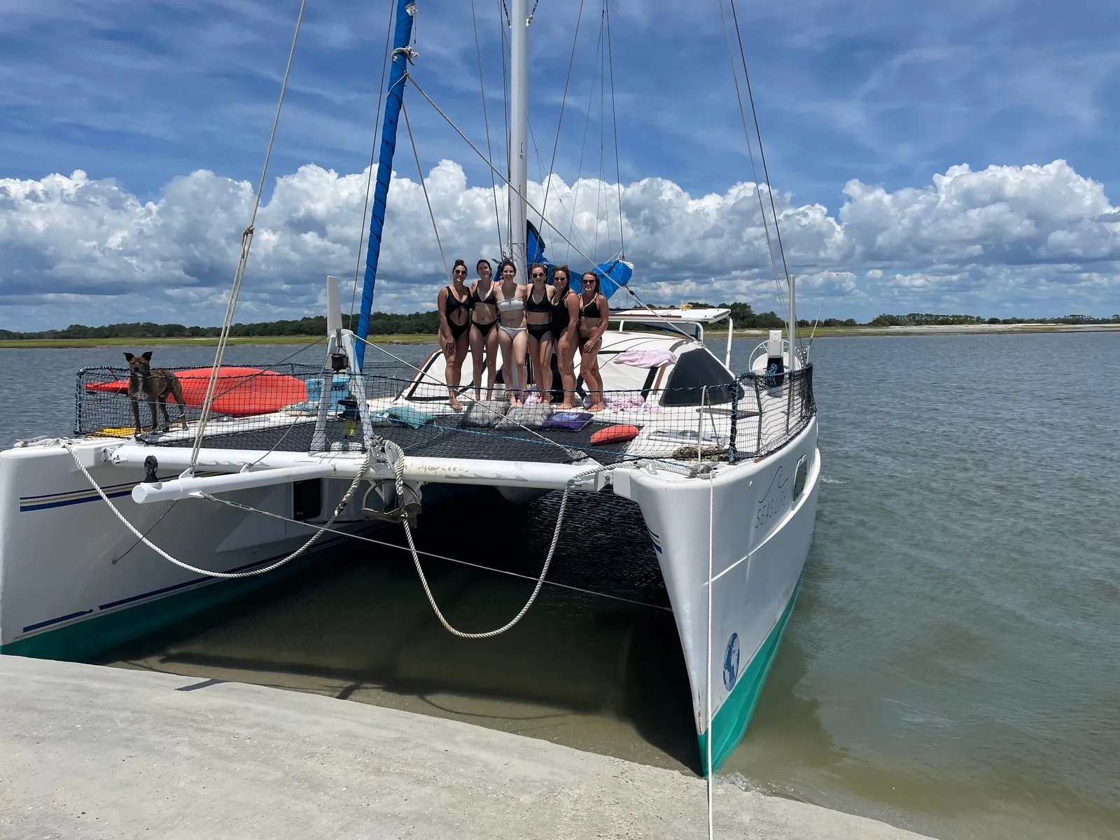 A group of guests relaxing on the bow trampolines of the sailing catamaran