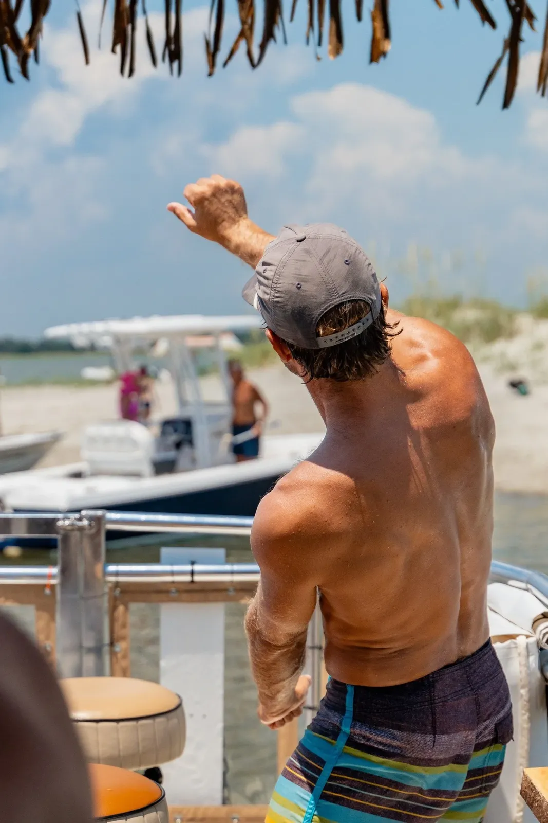 A guest celebrating on a sandbar beside anchored boats